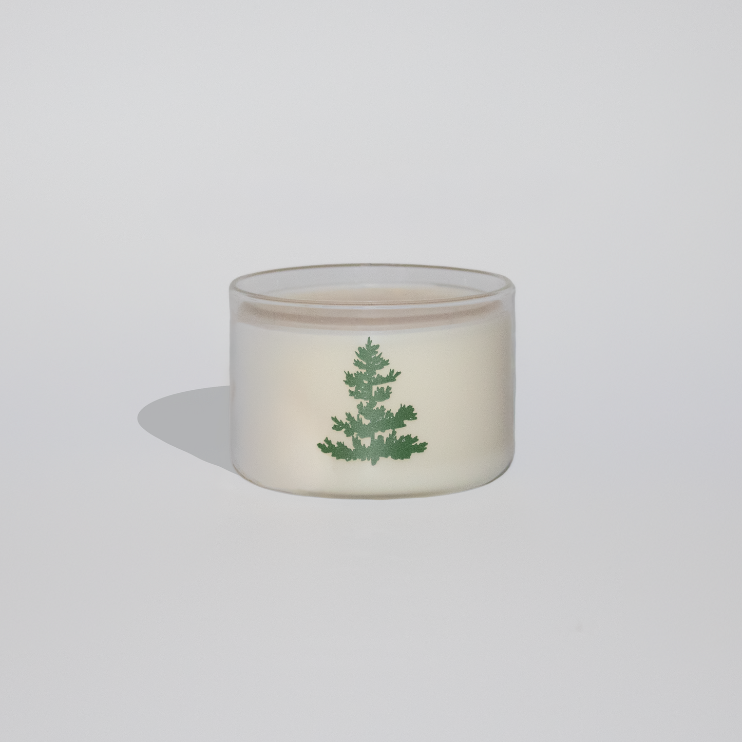 Small glass container with a green leaf design on a white background