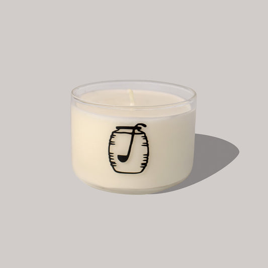 White candle with a black logo on a light gray background