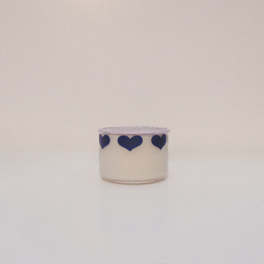 Small candle with blue heart designs on a light background