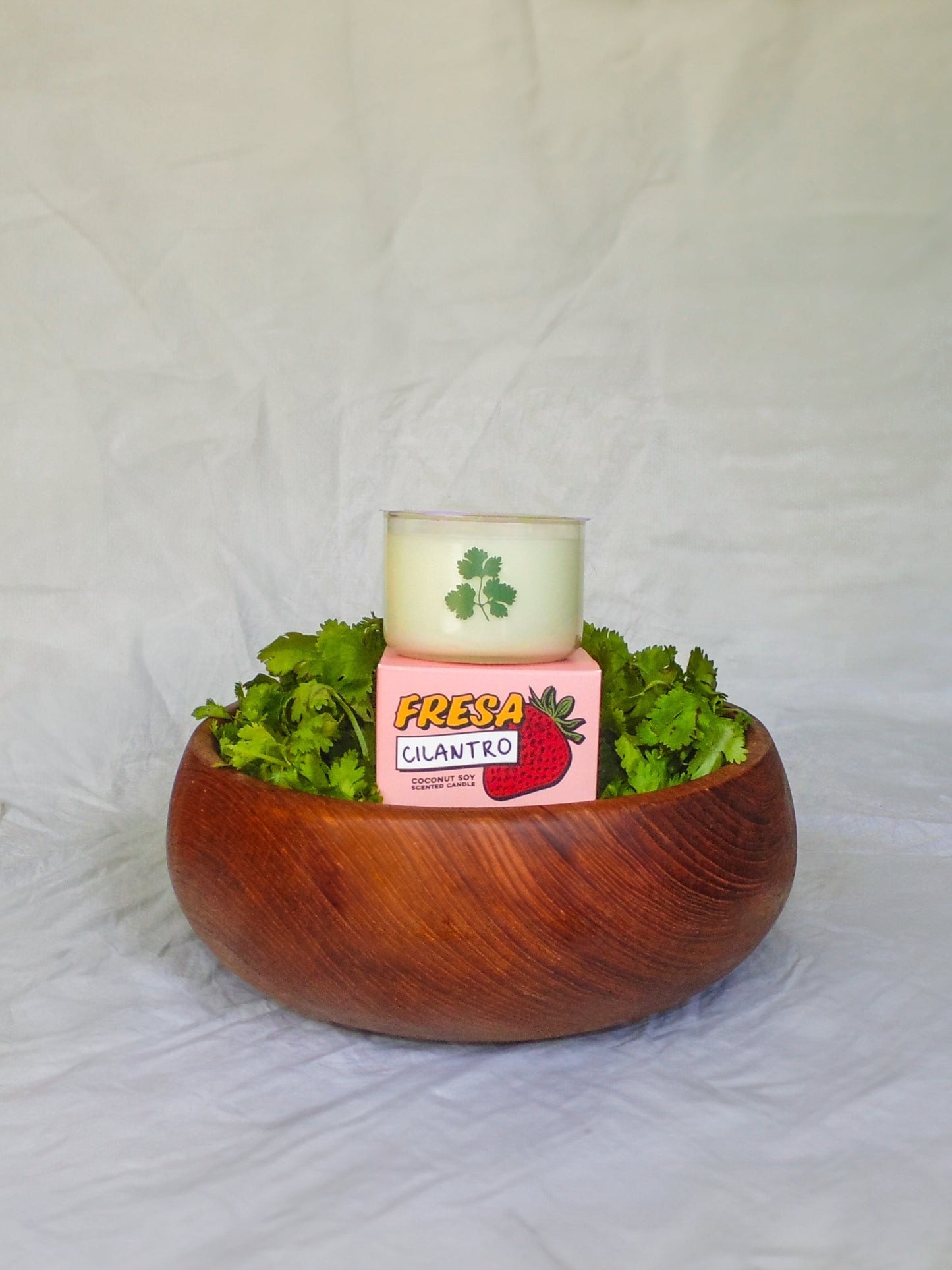 Wooden bowl with fresh cilantro and a pink container labeled 'Fresa Cilantro' on a white background