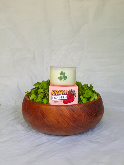 Wooden bowl with fresh cilantro and a pink container labeled 'Fresa Cilantro' on a white background