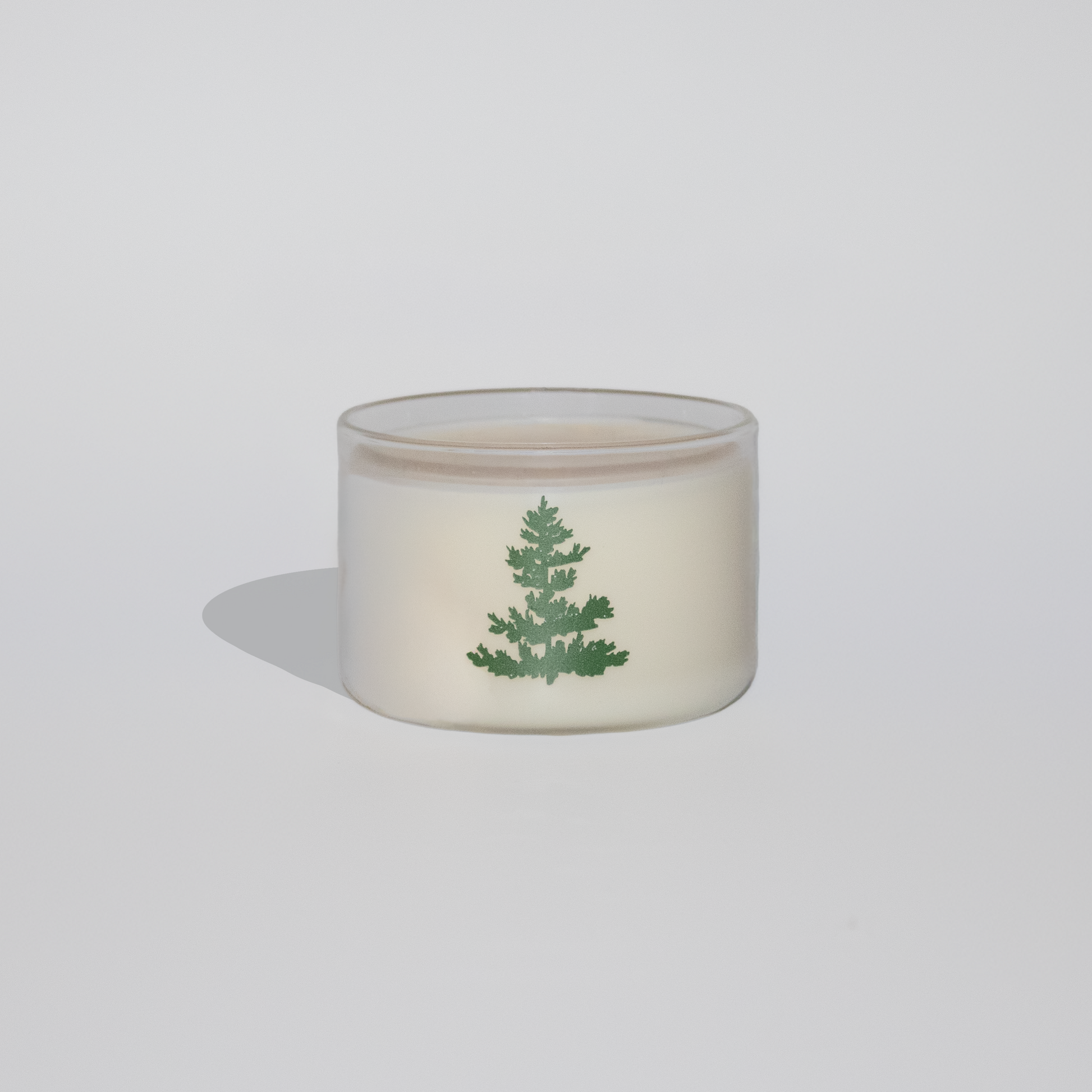 Small glass container with a green leaf design on a white background