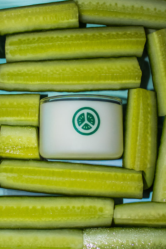 Cucumbers arranged around a small container with a green cucumber logo on a blue background