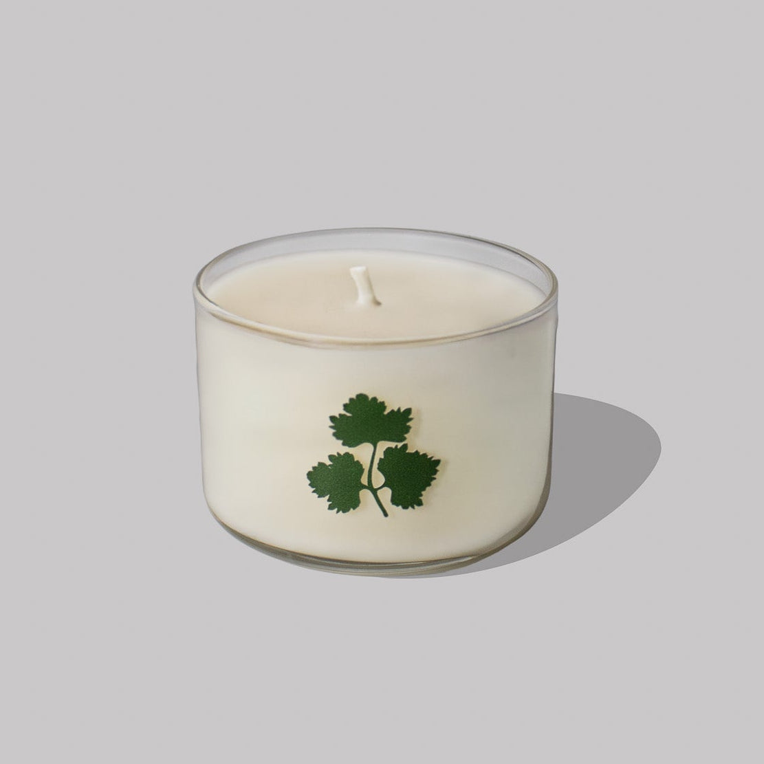 Candle with a green leaf design on a light gray background