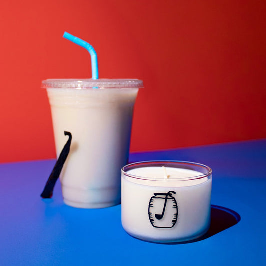Candle with a music note design next to a plastic cup with a straw on a red and blue background
