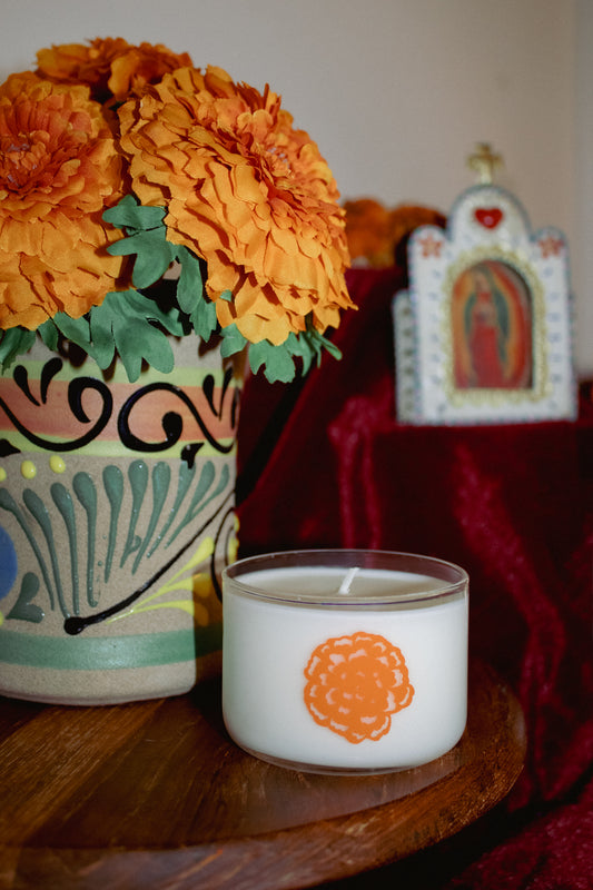 Candle with floral arrangement and religious icon in the background