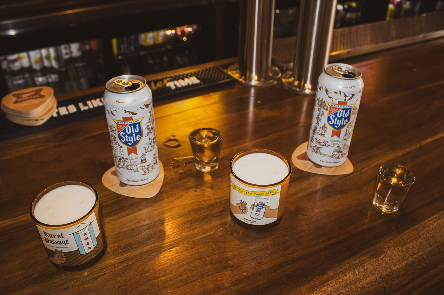 Old Style beer cans and glasses on a bar counter with a dimly lit background.