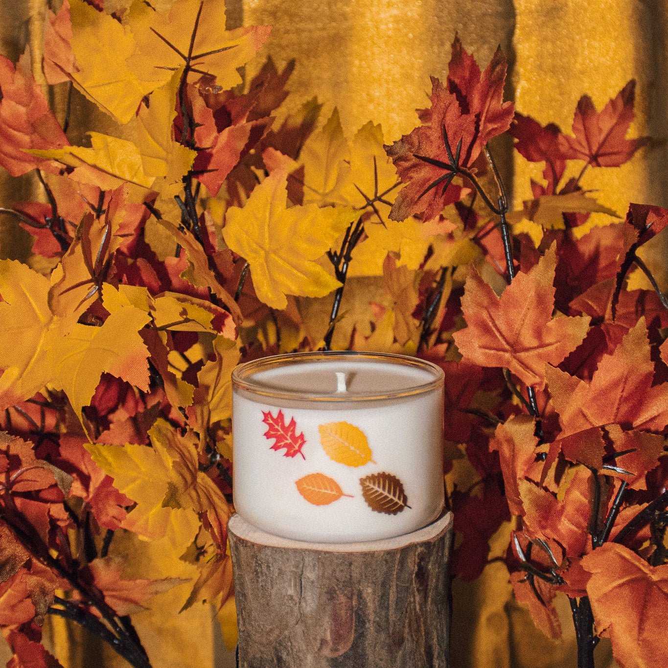 Candle with leaves decals surrounded by leaves
